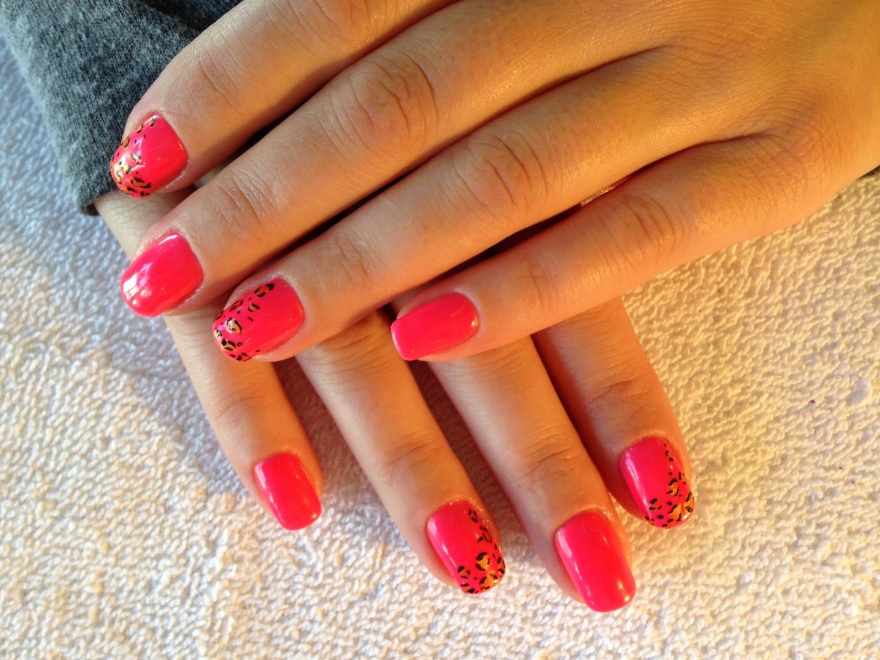 Coral pink gel manicure with leopard-print accent nails, done at Lush Nails in Longmont